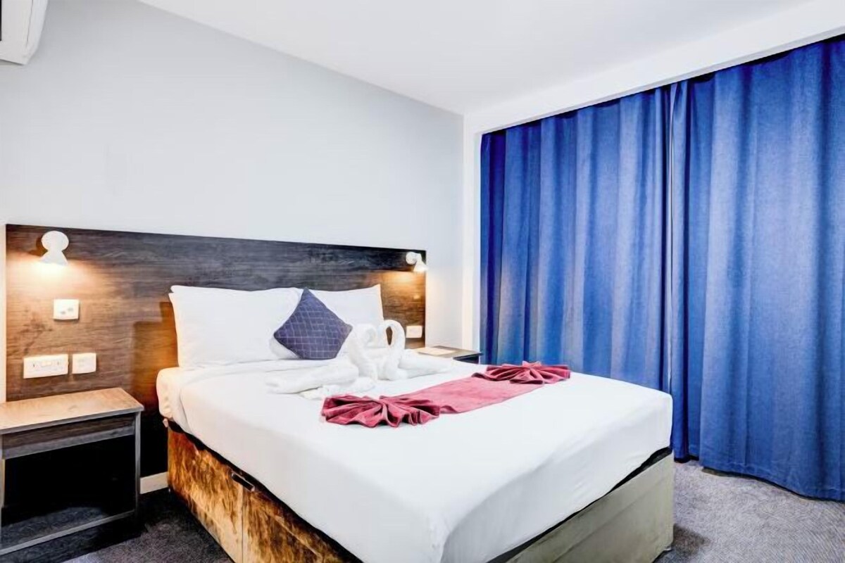 A neatly made bed with white linens, a wooden headboard, and a pink decorative item.