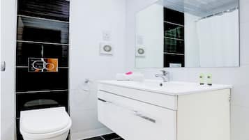 Un baño moderno con tocador blanco, inodoro y un espejo grande.