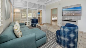 Ein modernes Wohnzimmer mit einem Ecksofa, einem blauen Sessel und einem flachbildfernseher an der Wand.