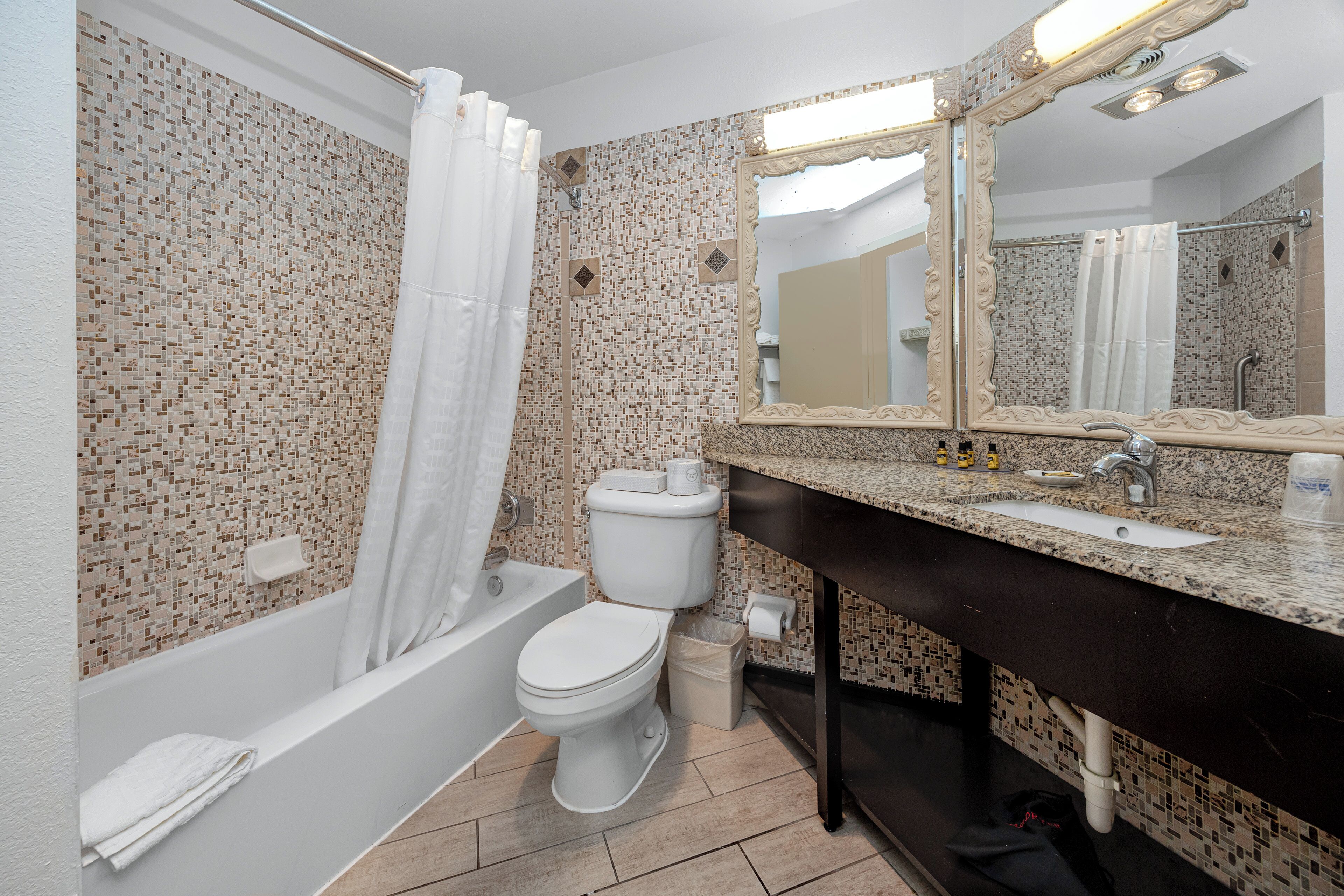 Une salle de bain avec une baignoire, des toilettes, un lavabo et un grand miroir.