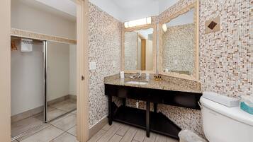 Un baño con piso de baldosas, un lavamanos con espejo y un inodoro.