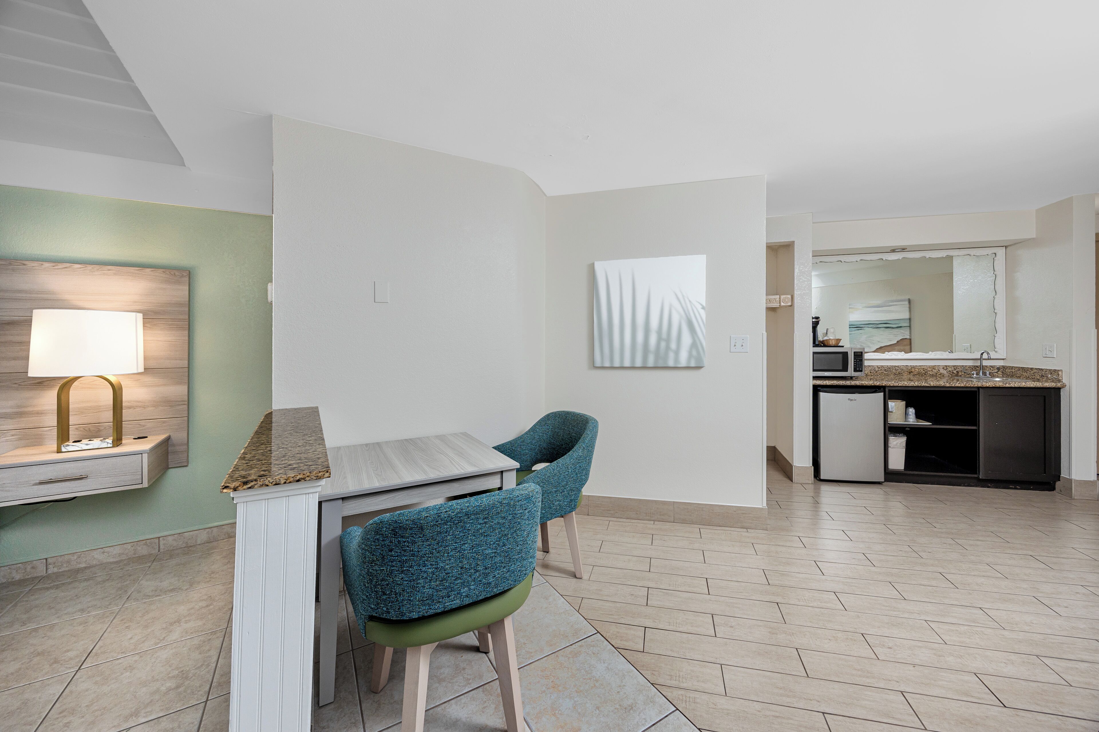 A modern kitchen with a granite countertop, a built-in microwave, and a small refrigerator.