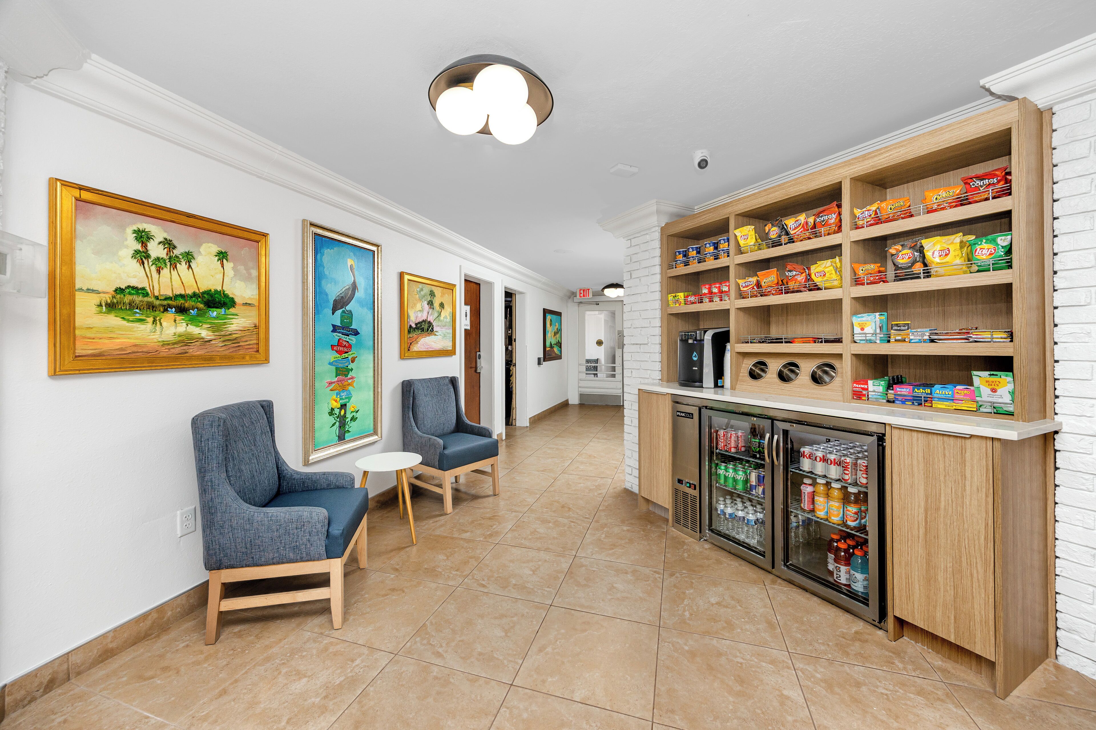 A hallway with seating, artwork, and a snack bar with various food items.