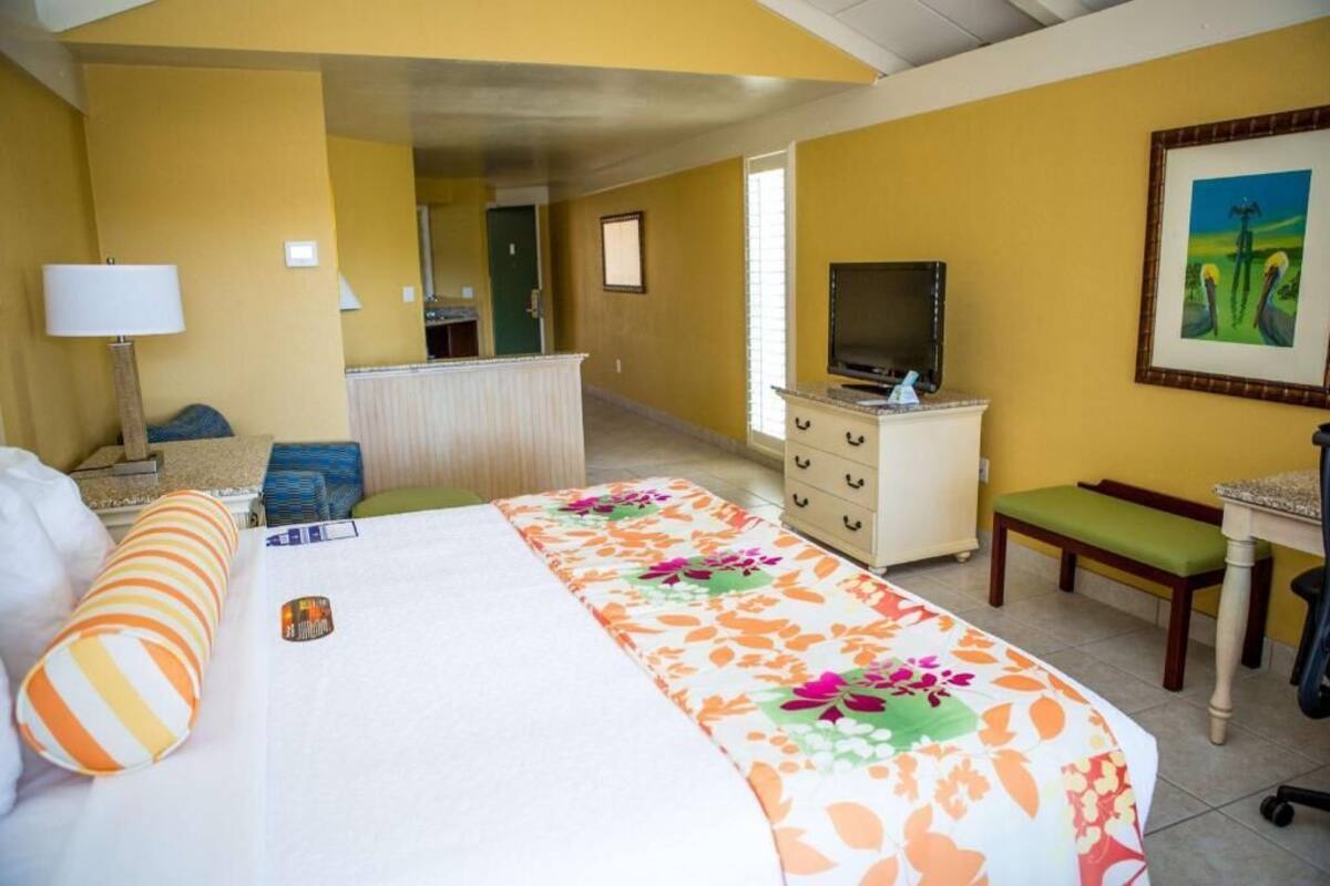 A hotel room with a bed, a desk, a television, a chair, and a painting on the wall.