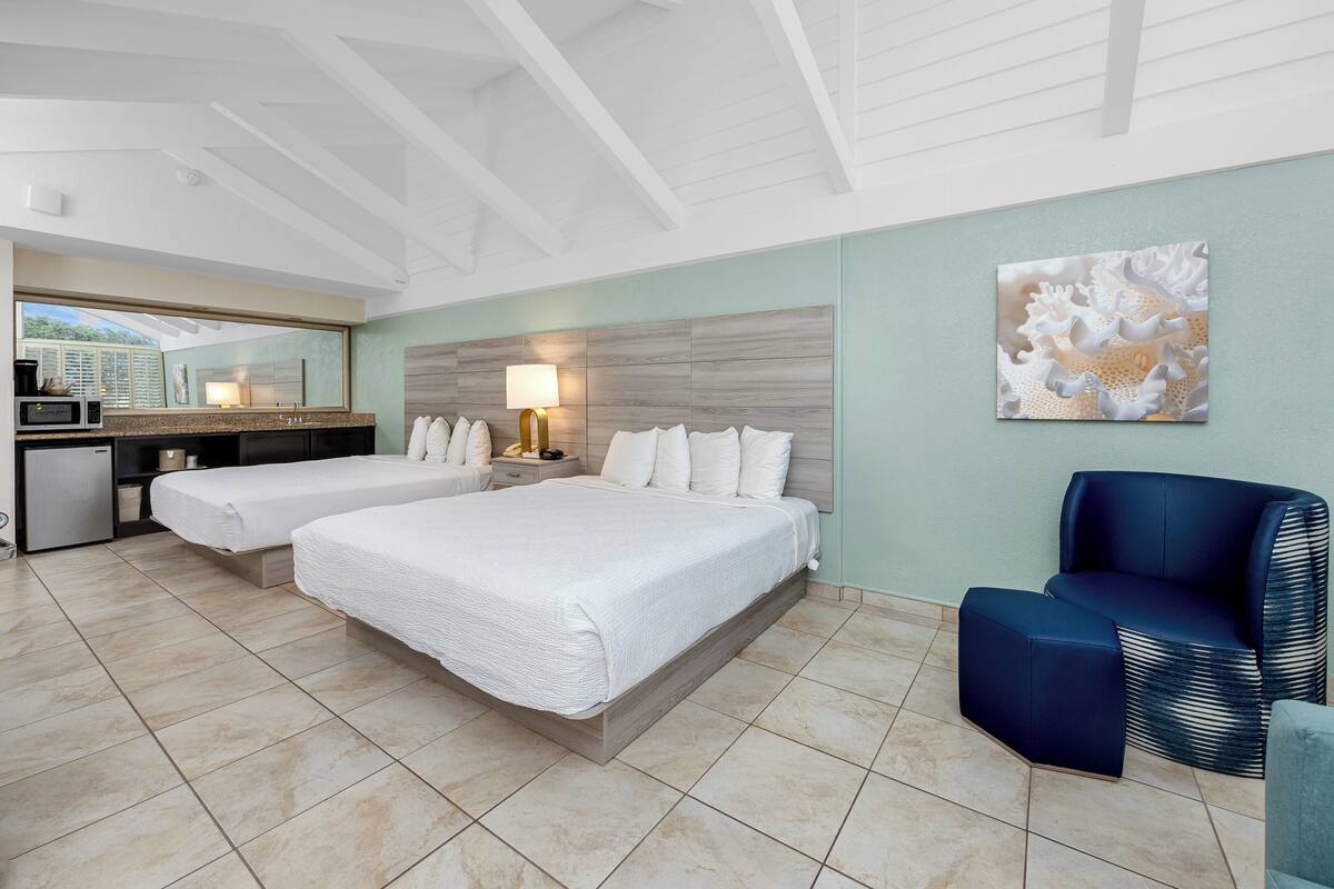 A hotel room with a large bed, a desk with a lamp, a microwave, and a view of the outdoors.