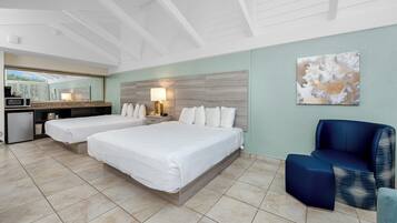 A hotel room with a large bed, a desk with a lamp, a microwave, and a view of the outdoors.