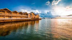 Ein Hotel am Wasserufer mit mehreren Bungalows über dem Wasser, einer Anlegestelle und einem ruhigen Meer.