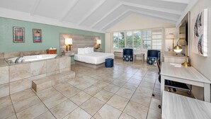 Ein geräumiges Schlafzimmer mit einem großen Bett, einer Sitzecke mit Sesseln, einem Schreibtisch und einer Badewanne.