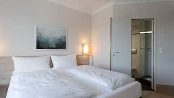 Een hotelkamer met een groot bed, een schilderij aan de muur en een badkamer door een open deur zichtbaar.
