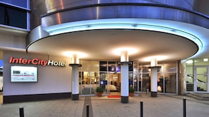 Entrada del Hotel InterCity con un diseño moderno, que presenta una fachada curva, puertas de vidrio y un cartel.