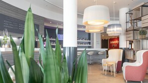 Un moderno vestíbulo de hotel con zona de bar, asientos y un panel de menú visible.