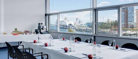 A conference room with a long table set for a meeting, large windows with a city view, and modern chairs.