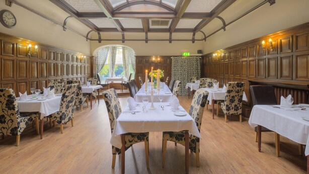 A dining area with long tables set for service, wooden paneling on the walls, and a skylight ceiling. - Cobden Hotel Birmingham (Birmingham)