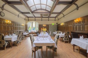 A dining area with long tables set for service, wooden paneling on the walls, and a skylight ceiling. - Cobden Hotel Birmingham (Birmingham)
