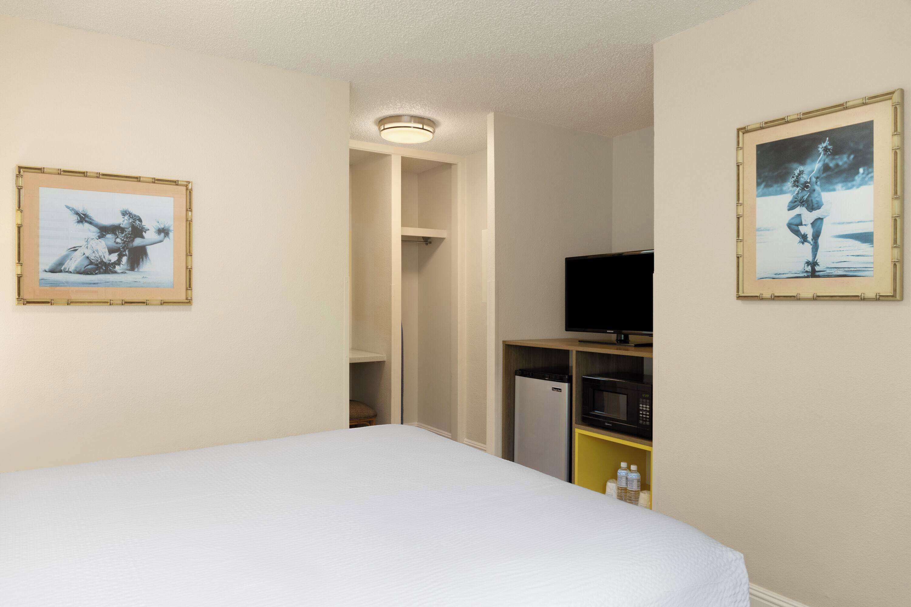 Ein Hotelzimmer mit einem Bett, einem Fernseher, einer Mikrowelle und einem Kühlschrank.