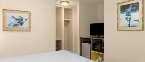 A hotel room with a bed, a television, a microwave, and a refrigerator.