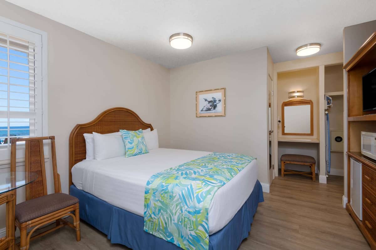 A hotel room with a bed, a chair, a desk, a television, and a bathroom.