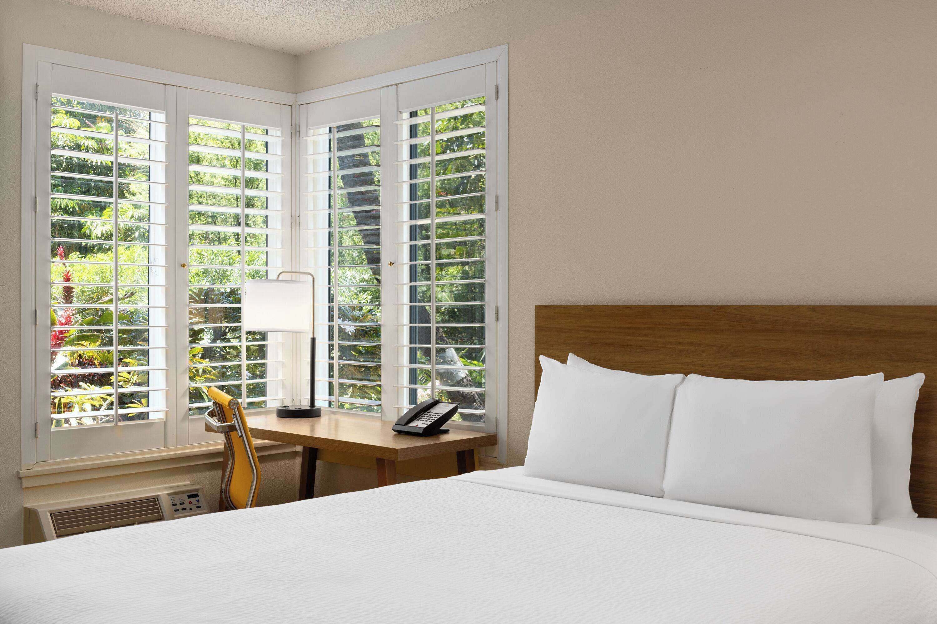 Een hotelkamer met een bed, een bureau met een telefoon en een stoel.