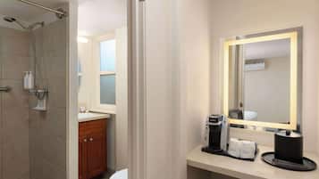 A bathroom with a shower, toilet, sink, and a mirror with a light.