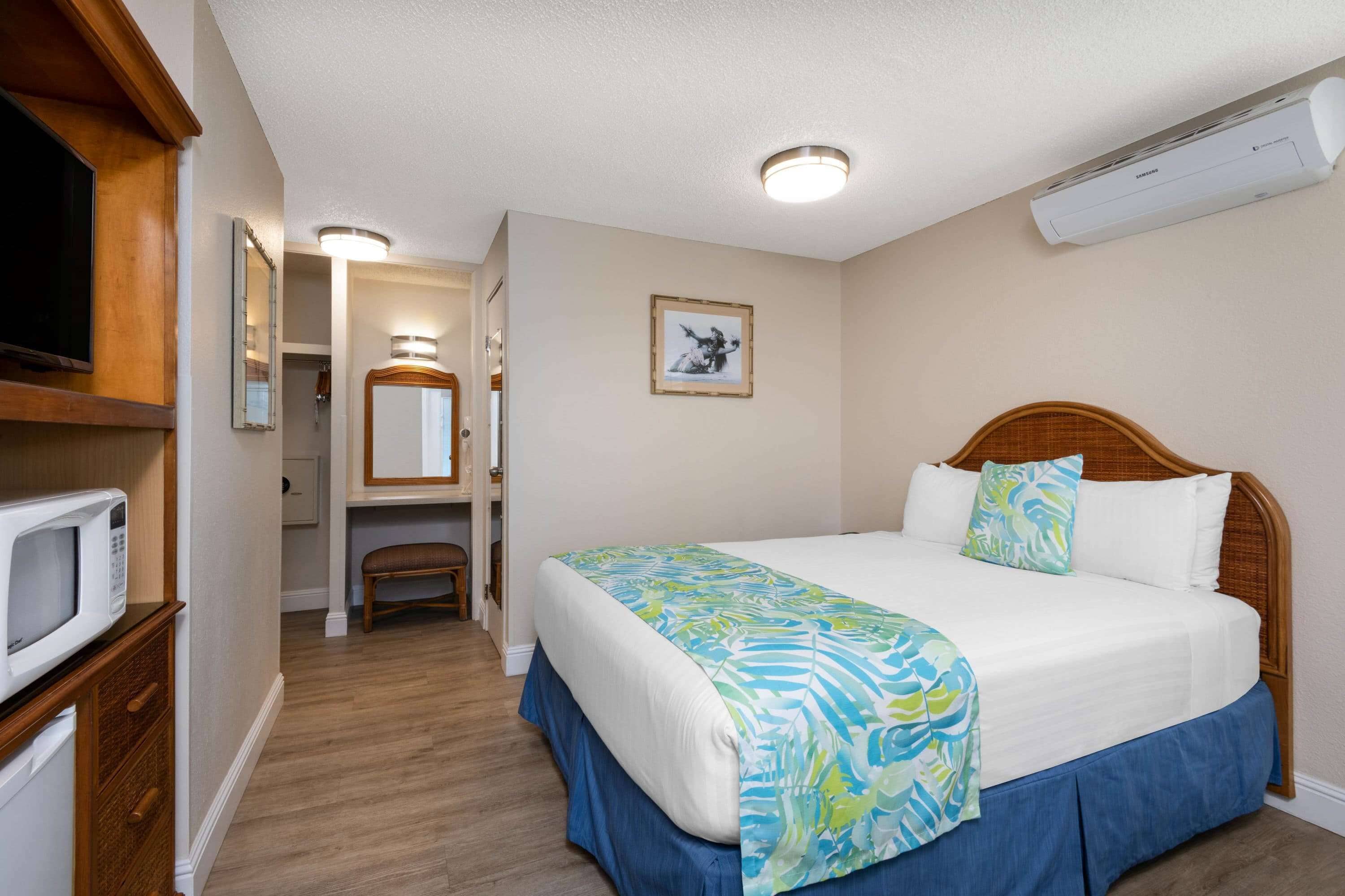 Habitación de hotel con cama, televisor, microondas y baño visible a través de una puerta abierta.