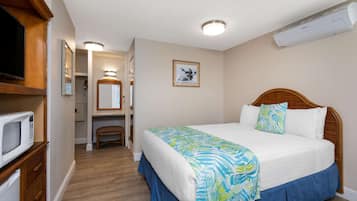 Habitación de hotel con cama, televisor, microondas y baño visible a través de una puerta abierta.