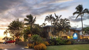 A hotel with a sign for Days Inn by Wyndham, surrounded by palm trees and a well-maintained lawn.