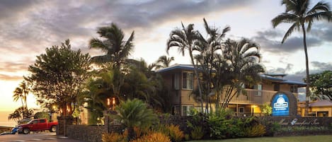 A hotel with a sign for Days Inn by Wyndham, surrounded by palm trees and a well-maintained lawn.