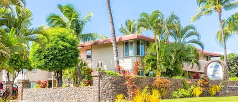 A hotel with a stone wall, palm trees, and a sign for Days Inn.