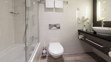 A modern bathroom with a glass-enclosed shower, a white toilet, and a sink with a mirror above it.