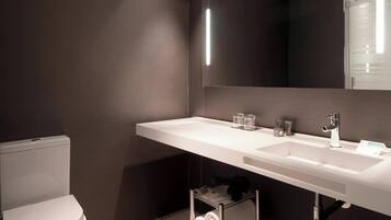 Un baño moderno con un lavamanos blanco, un espejo y un inodoro.