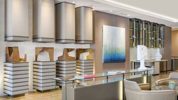 A modern reception area with a glass desk, seating, and a decorative wall with shelves.