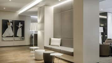 A modern hotel lobby with a seating area, a reception desk, and artwork on the walls.