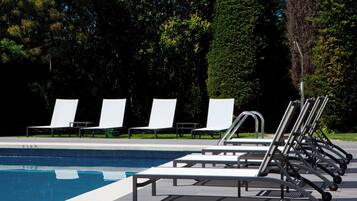 A swimming pool with lounge chairs and a metal structure.
