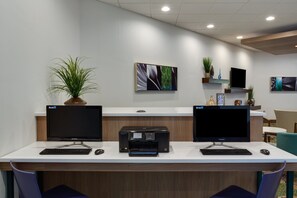 A modern office space with two desks, each with a computer monitor, keyboard, and mouse. There are two printers on the desks, and the walls are adorned with framed artwork. - Holiday Inn Express Wilkesboro by IHG (North Wilkesboro)