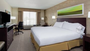 Habitación de hotel con una cama grande, un escritorio con televisor, una silla y una ventana con cortinas.