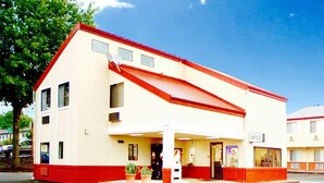 Un edificio de dos pisos con techo rojo y paredes blancas, que muestra una entrada visible y un letrero que dice 