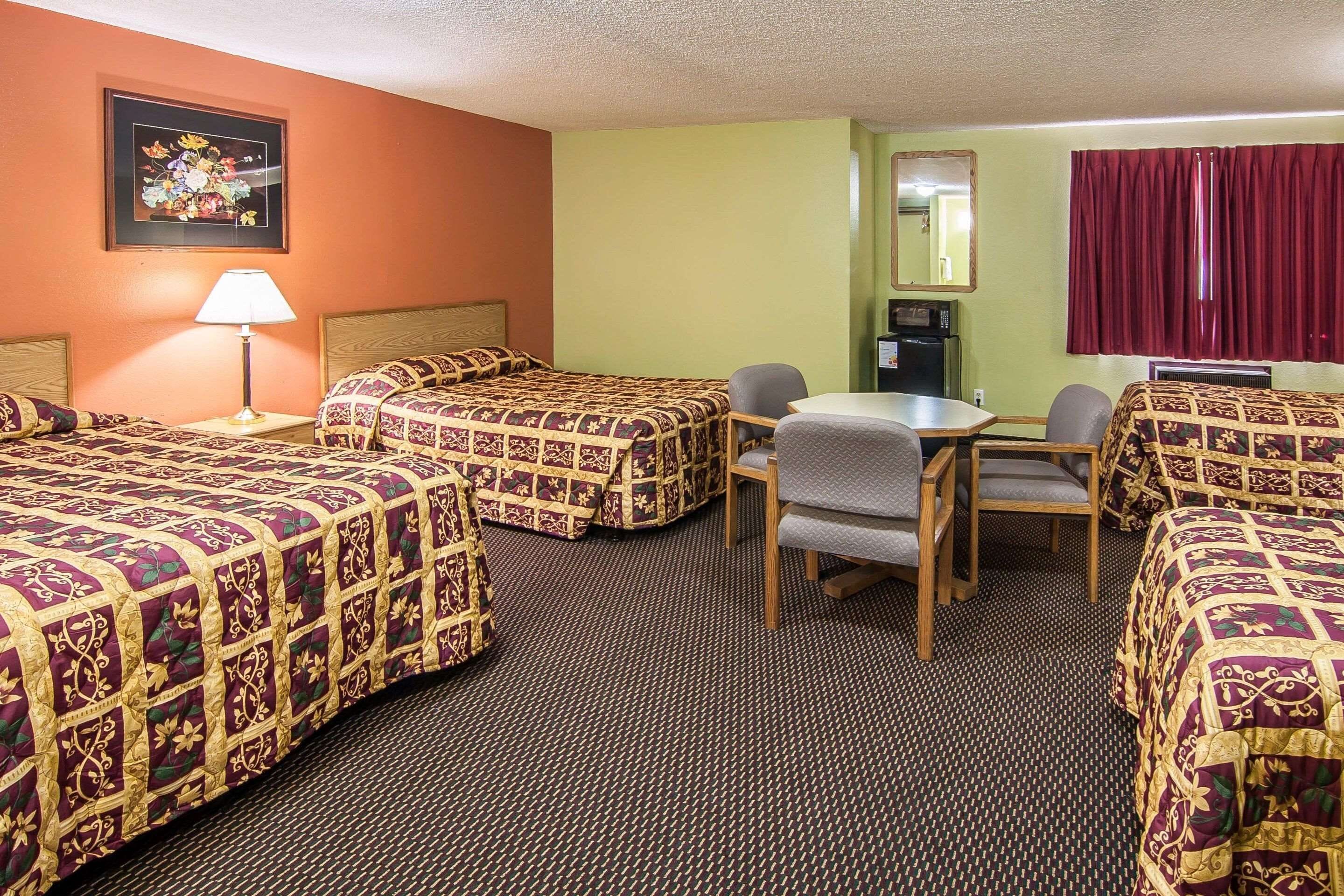 A hotel room with four beds, a desk, and a chair.