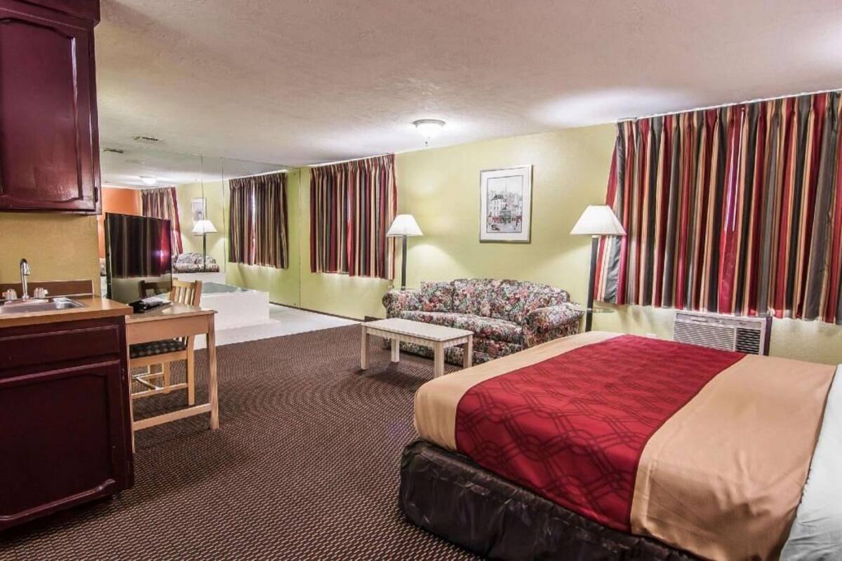 Quarto de hotel com cama, sofá, escrivaninha e espelho.