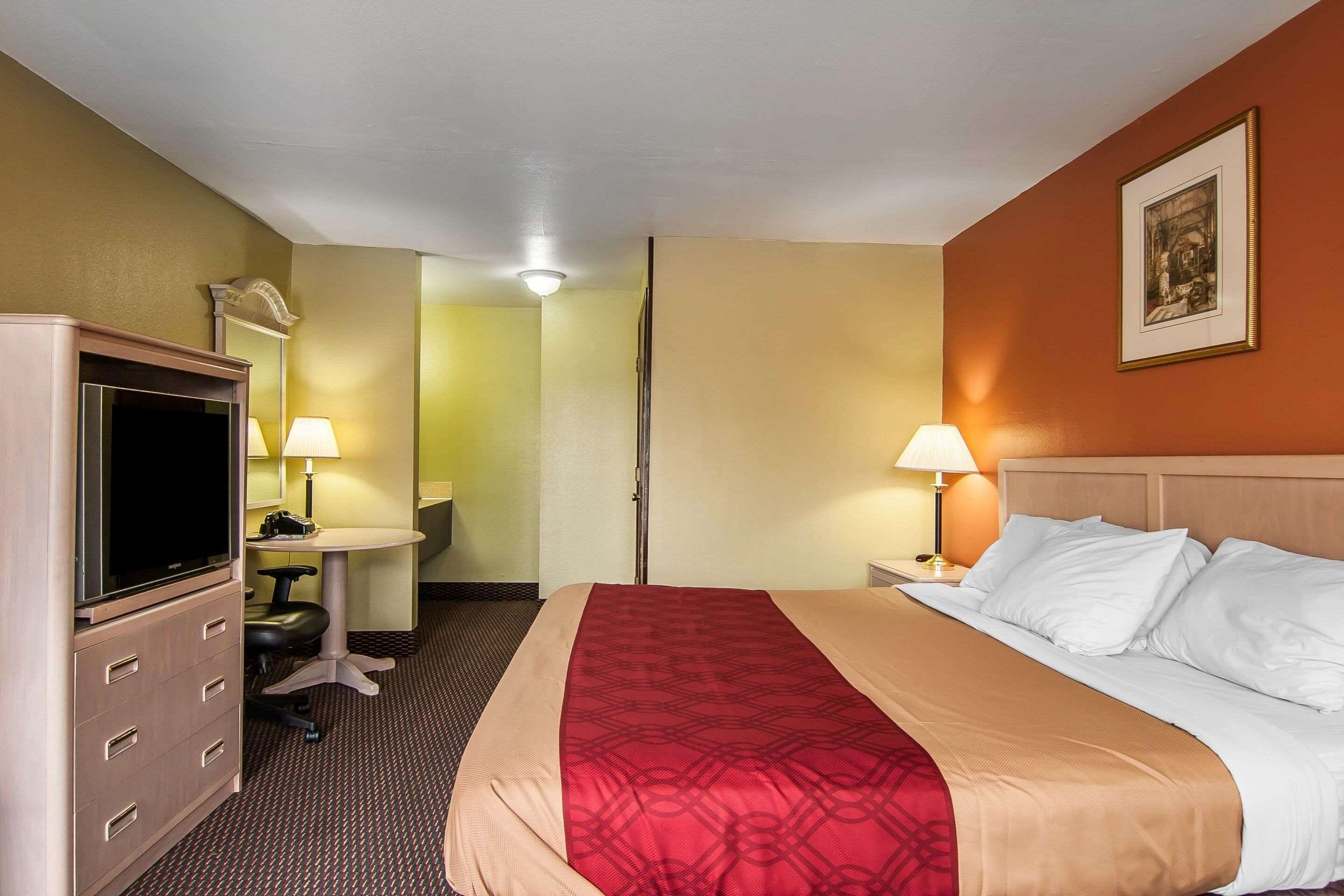 Ein Hotelzimmer mit Bett, Schreibtisch, Stuhl, Fernseher und zwei Lampen.