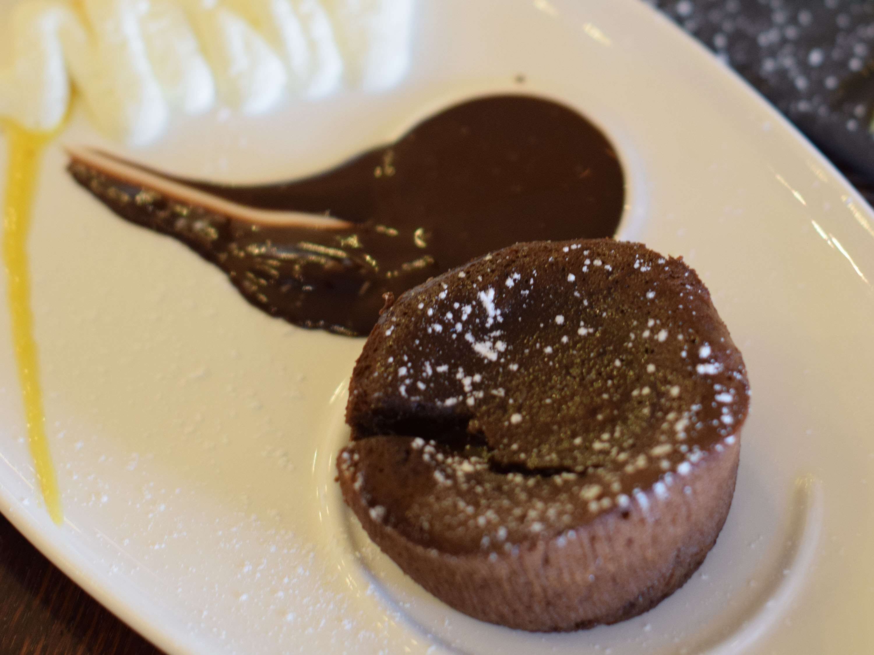 Um prato de sobremesa com um bolo de chocolate derretido e uma bola de sorvete de baunilha.