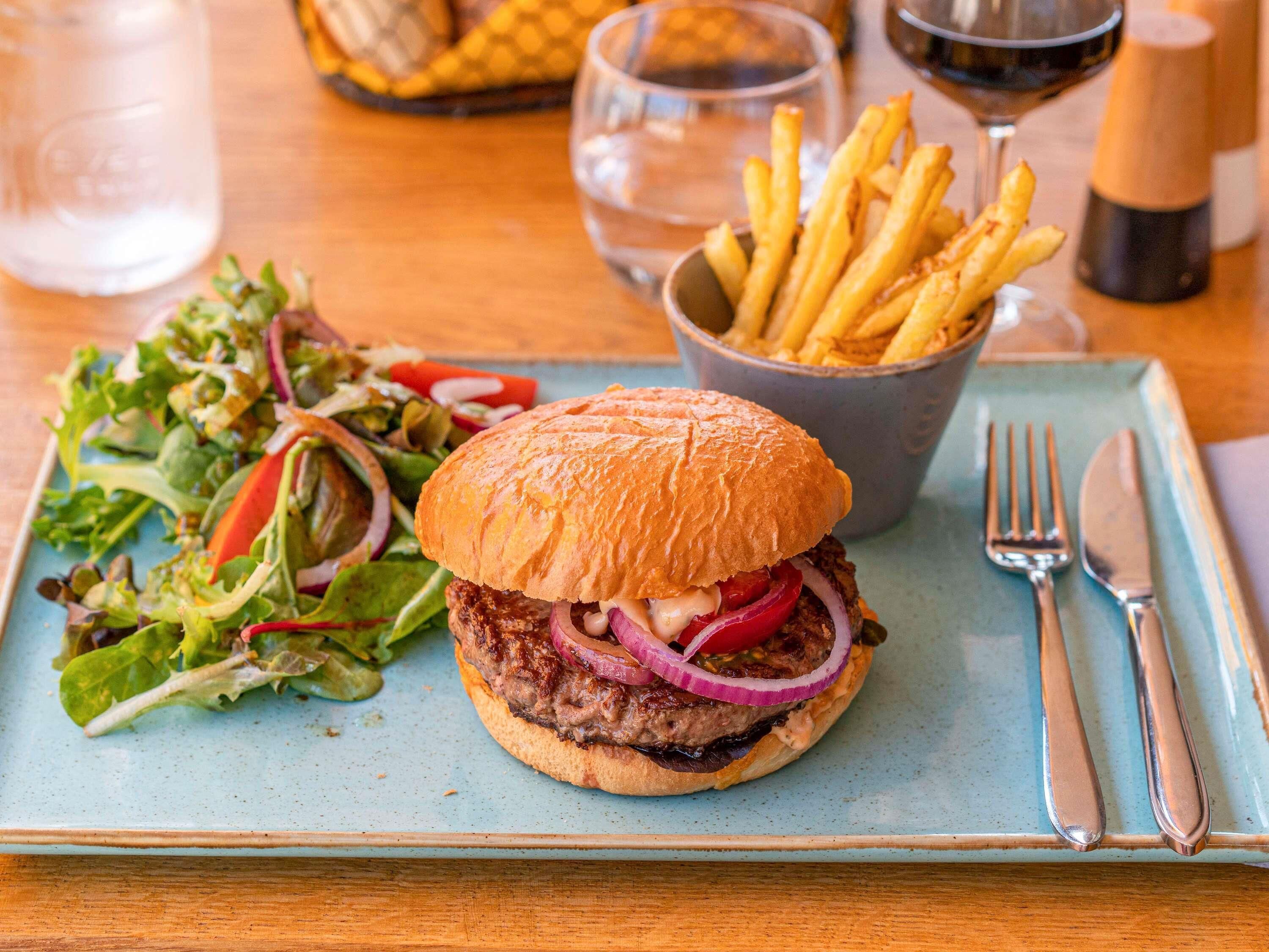 A meal with a burger, fries, and salad on a plate.