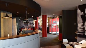 Ein modernes Interieur mit einer geschwungenen Rezeption, Pendelleuchten und einer Kombination aus Rot- und Neutraltönen.