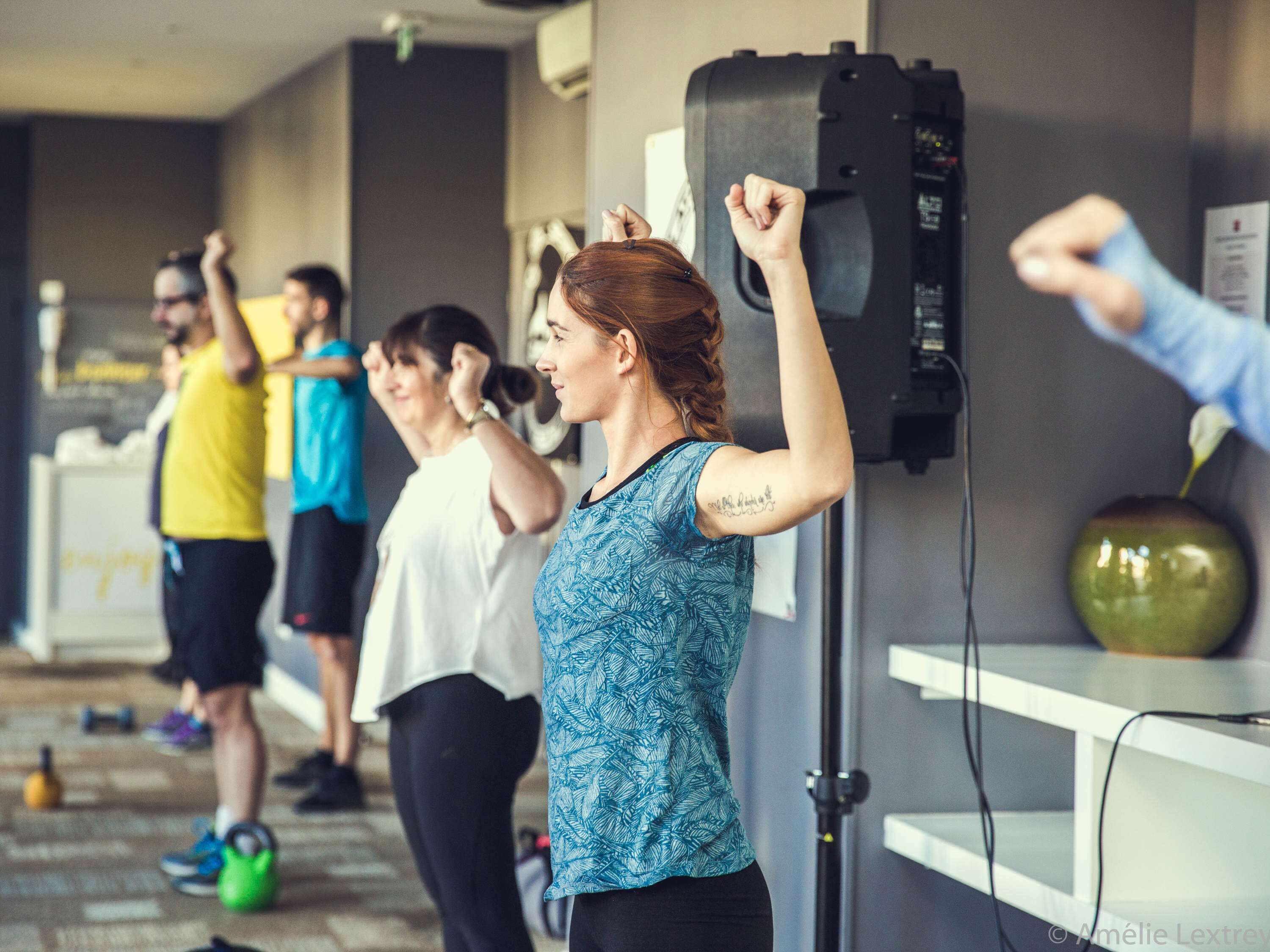 A group of people exercising in a gym with weights and exercise equipment.