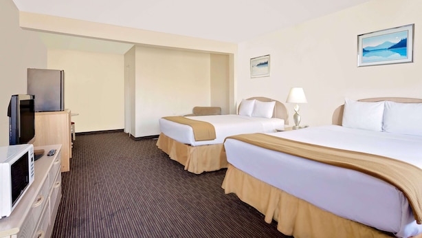 A hotel room with two beds, a TV, a microwave, and a painting on the wall. - Knights Inn Page (Page)