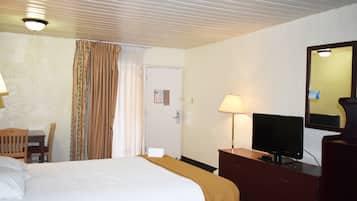 A hotel room with a bed, a desk with a chair, a television, and a dresser.
