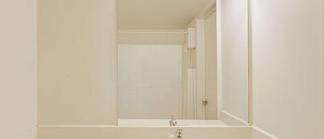 A bathroom with a white sink, a mirror with lights, and a door in the background.