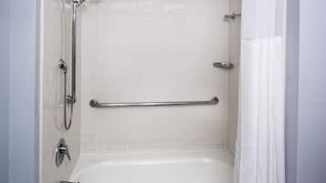 A bathroom with a white bathtub, a shower with a handheld showerhead, and a grab bar installed for safety.