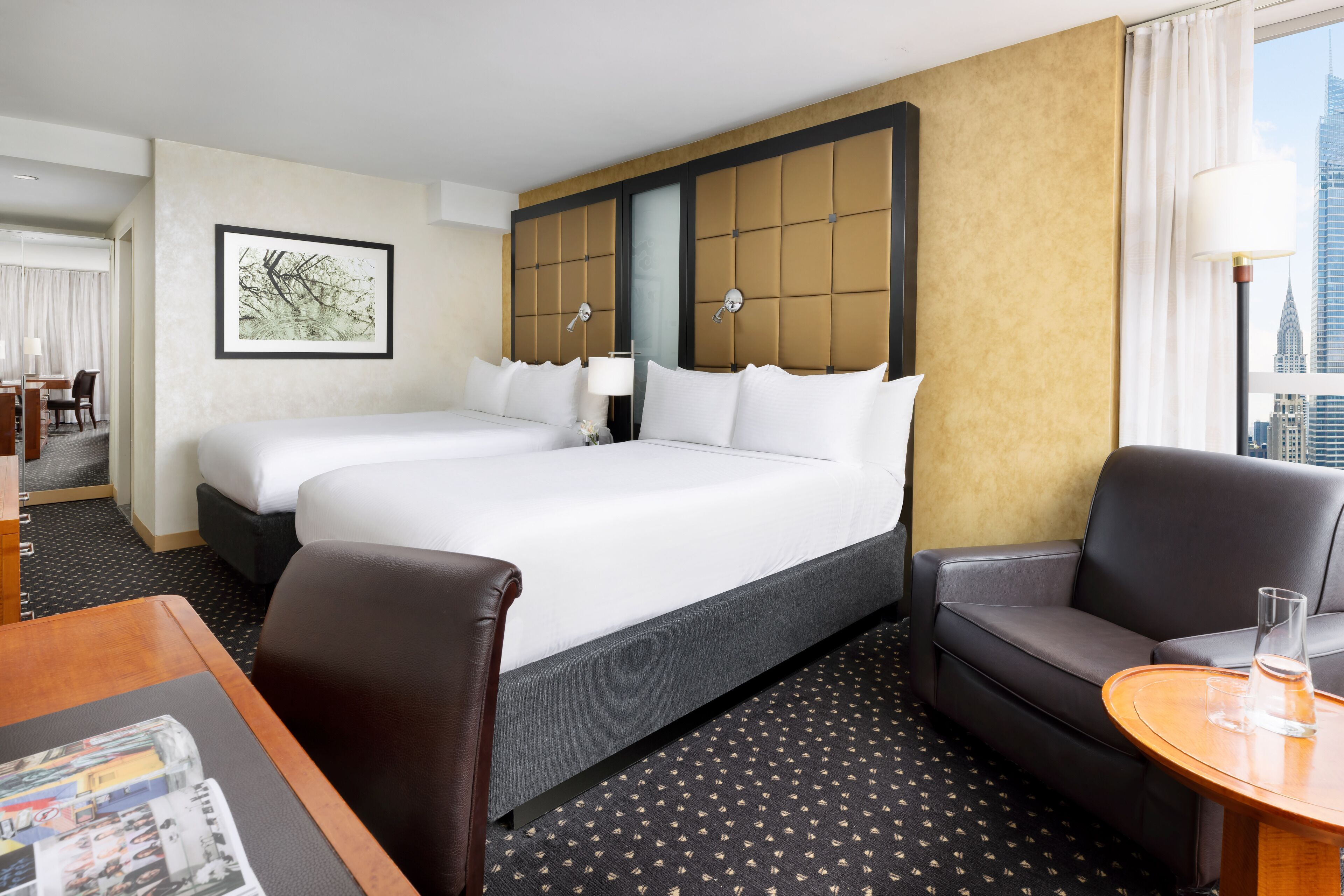 Une chambre d’hôtel avec un grand lit, un canapé, un bureau et une vue sur la ville.