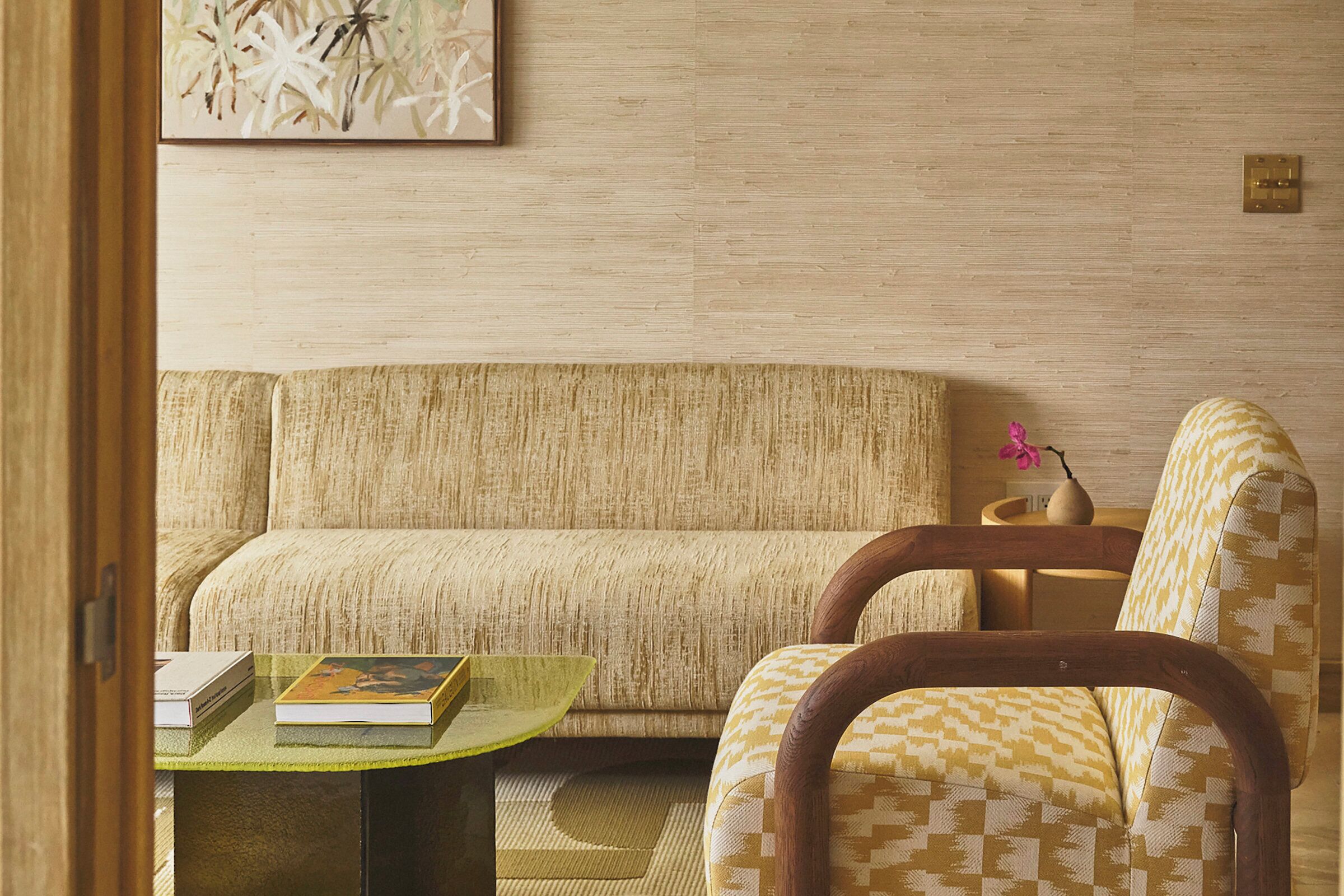 Un salon avec un canapé, un fauteuil et une petite table sur laquelle sont posés des livres.