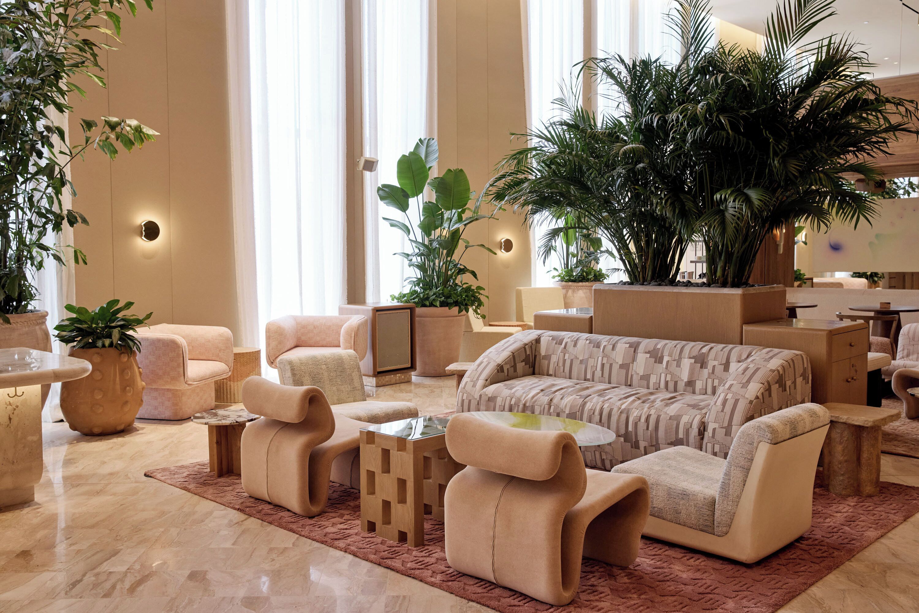 Un espace de détente moderne comprenant un canapé, des fauteuils, une table basse et des plantes en pot.